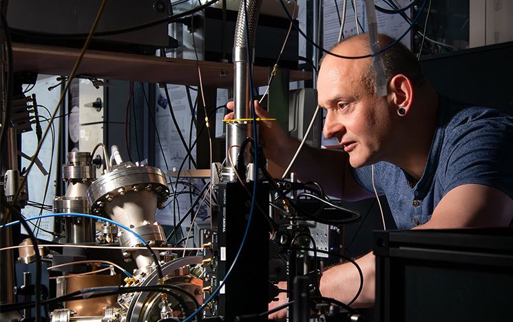 A physics professor using quantum technology equipment in a dark lab setting