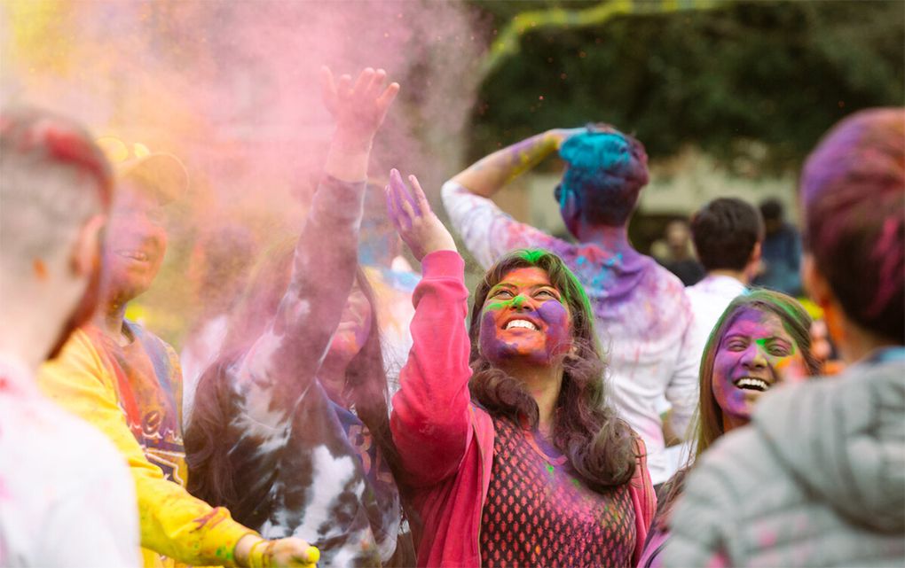 A gathering of students covered in powder paint, enjoying the Holi festival