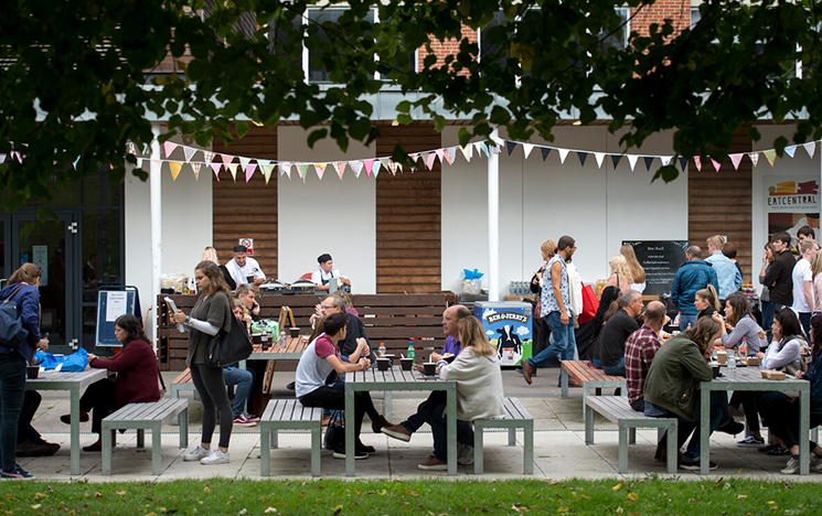 Students sitting on tables outside a uni building.