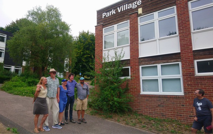 A group of alumni standing outstanding Park Village residences on campus.