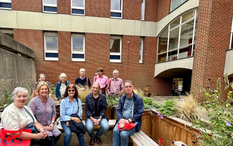 A group of alumni sitting outside a building on campus