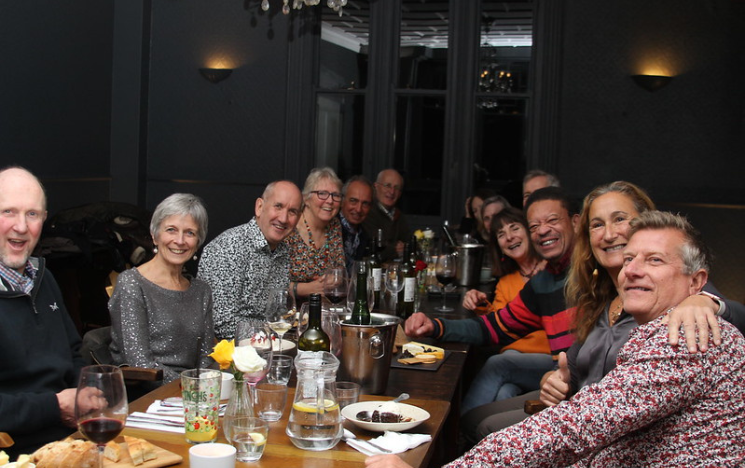 A group of alumni sitting around a table in a restaurant having drinks and dinner