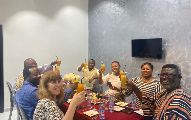 A group of alumni sitting around a table in a restaurant holding up drinks