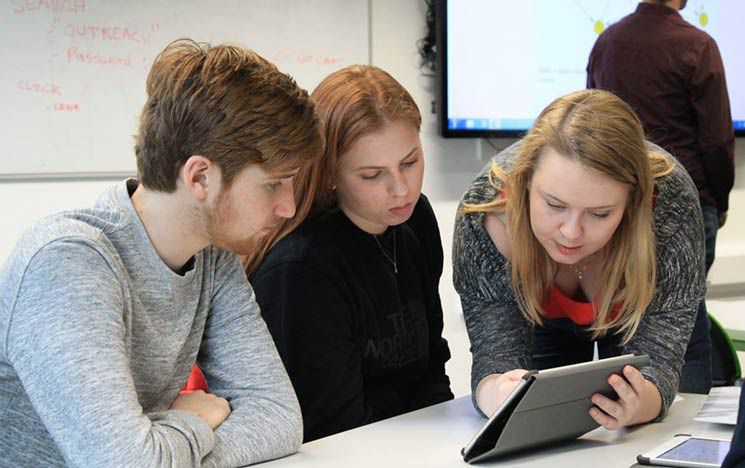 
A photo of a teacher and two students working on an iPad