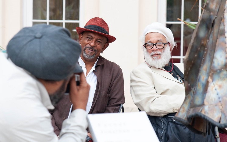 A man wearing a hat photographing two other men
