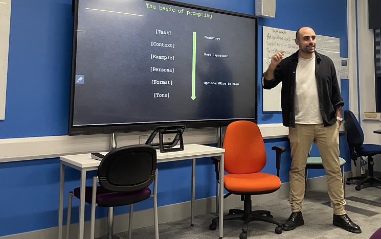 A man gesturing enthusiastically standing in front of a screen