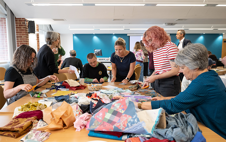A group of women gathered around a table of woven materials