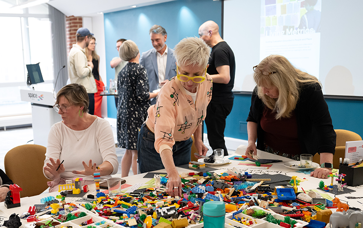 A group of women gathered around a table of lego blocks