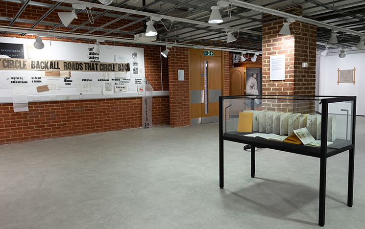 View of Pressing Matters exhibition space in University of Sussex Library, with art on the walls and in a display cabinet