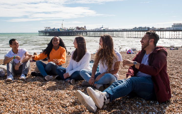 Summer School students talking and laughing on Brighton beach