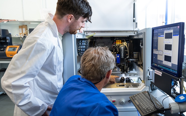 Two scientists in a lab looking into a gas sensing machine