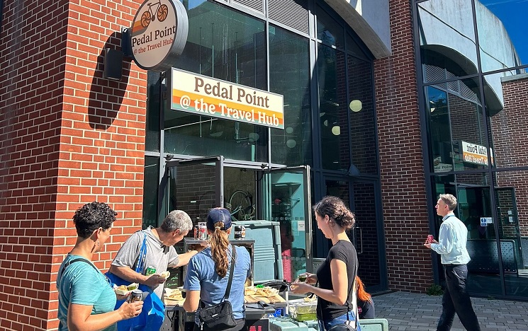 External view of the Pedal Point at the Travel hub shop, with a group of people gathered outside