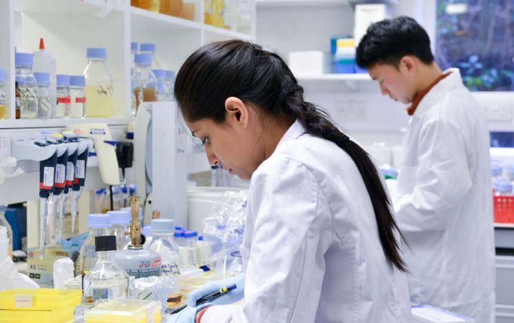 Students in white lab coats use equipment in biology labs Students in white lab coats use equipment in biology labs
