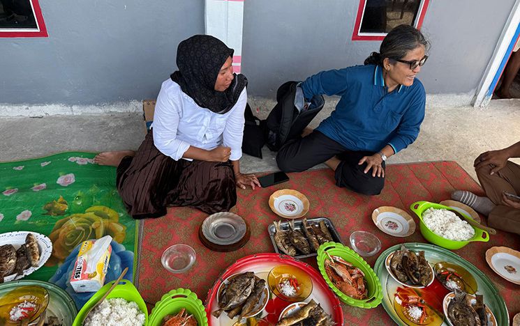 Rice and fish on plates on the ground with two people beside them