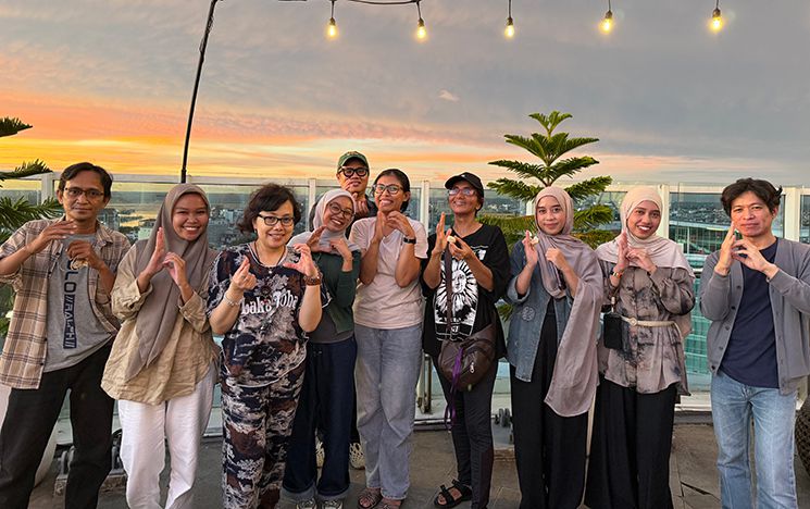Group of people at sunset with string of lights above them