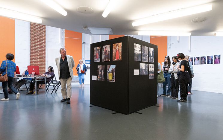 People looking at art on walls and central stand