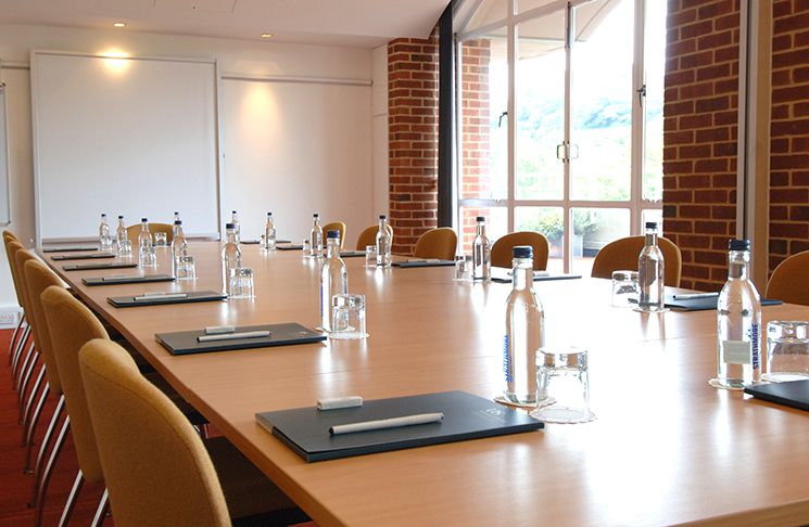 Table with water bottles, glasses and pads of paper