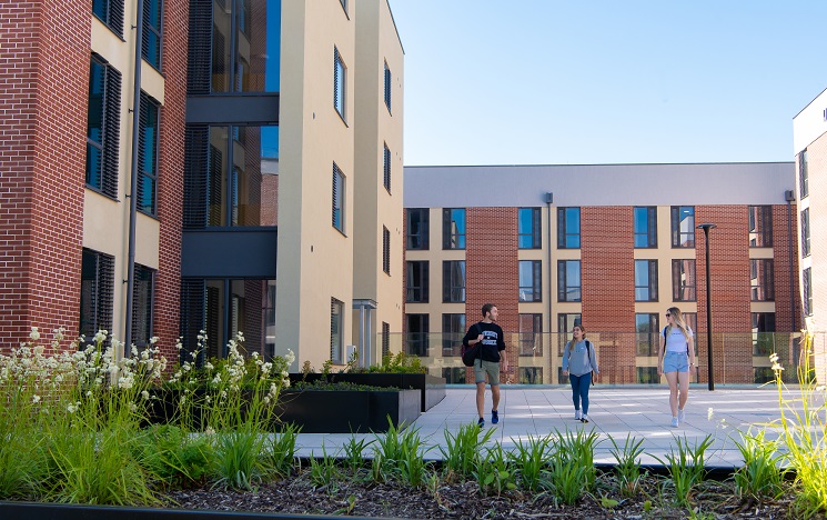 Modern accommodation blocks with flowerbeds and students outside