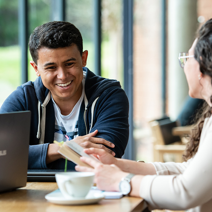 Postgraduate students chatting in Attenborough Centre cafe.