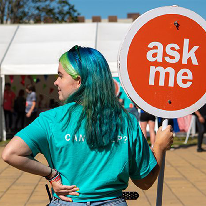 Student volunteer holding a sign saying 'ask me'