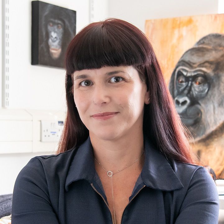 Dr Gillian Forrester in her office surrounded by paintings of primates