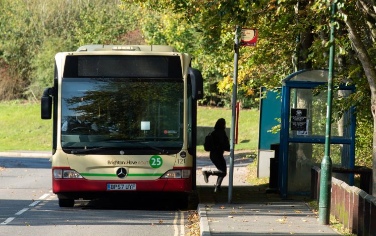 A student gets off a bus on campus