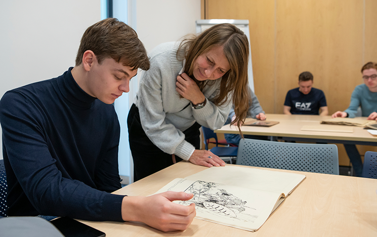 A staff member supporting a student studying historical archives