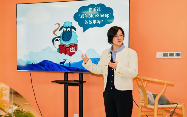 Alumna Kacci Xia standing in front of a screen giving a presentation.