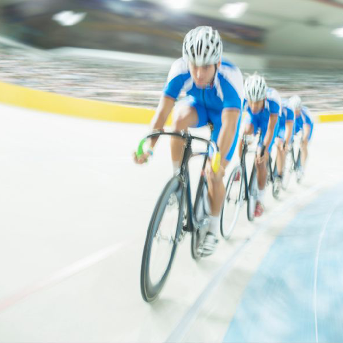 Four cyclists on a velodrome track.