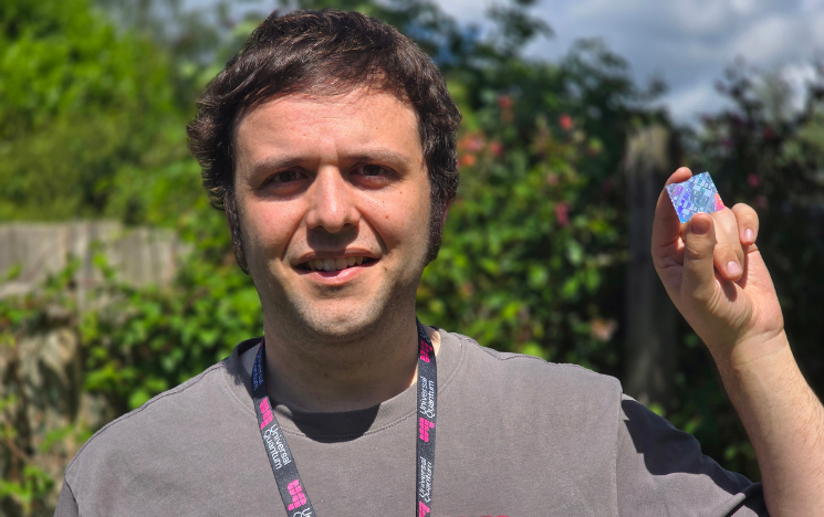 Zak Romaszko wearing a Universal Quantum lanyard holding up a quantum chip.