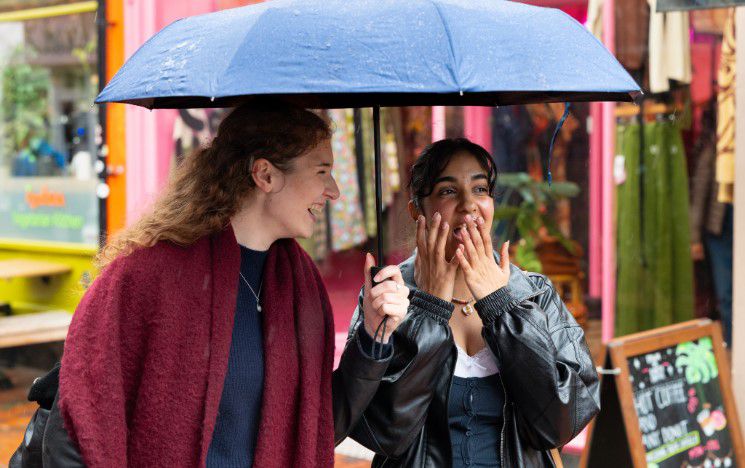 Two students share a laugh on a rainy day in Brighton Two students share a laugh on a rainy day in Brighton