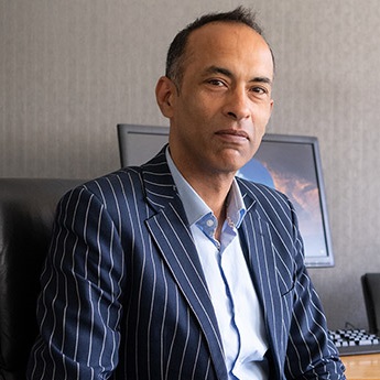 Man wearing pinstriped suit sitting at office desk