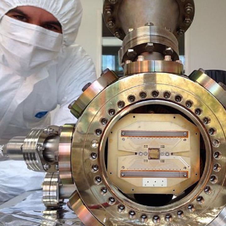 Person wearing a white safety suit and mask looking at a piece of machinery