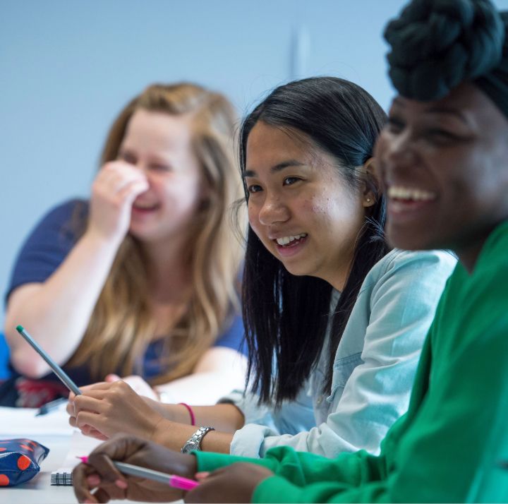Three students laugh together in class