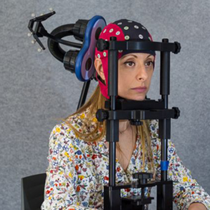 Participant wearing waveguard EEG cap on chinrest with a TMS coil placed on her head.