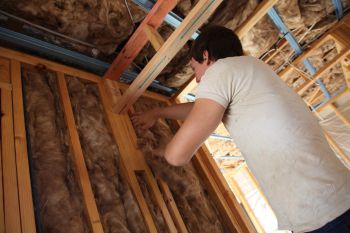 A man fits insulation into a house