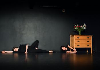 Still from drama performance - two females lie on the floor
