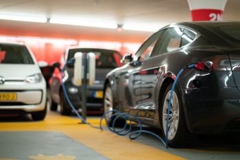 Black, white and grey electric cars are parked and being charged in a multi-storey car park