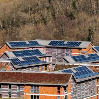 An aerial image showing a number of solar panels on the roofs of university buildings