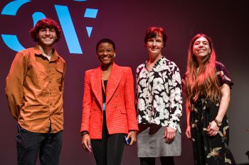 Four people stand on a drama stage