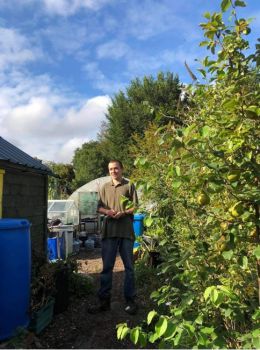 Young man in a green tshirt and jeans standing next to a shed