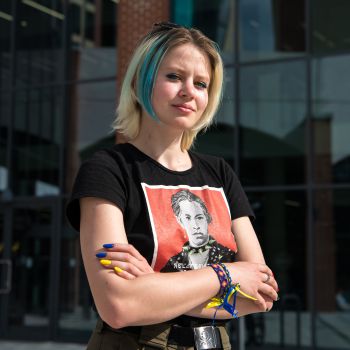 Violetta Korbina standing, arms crossed in front of the new Student Centre