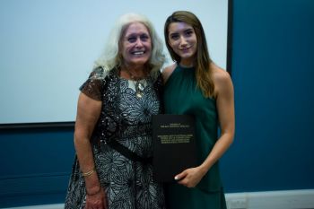 Two women holding a bound book as prize dissertation award