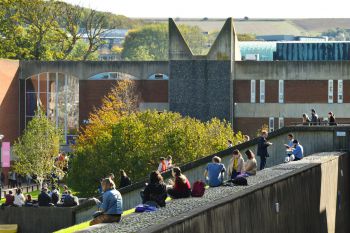 Campus shot of the University of Sussex, students outside the library