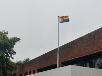 The rainbow progress pride flag flying over Sussex House on a cloudy day