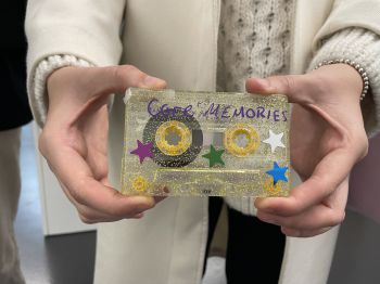 Person holding a cassette tape covered in glitter and stars with the text 