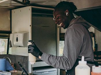 Smiling man serving food from a van