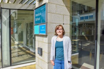 A photo of Eleanor Jayawant in front of the Medical School sign