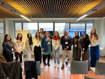 Dr Zahid Pranjol and some Sussex students standing, smiling, in front of a window