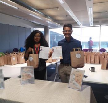 Two members of faculty standing at a table with recipe bags